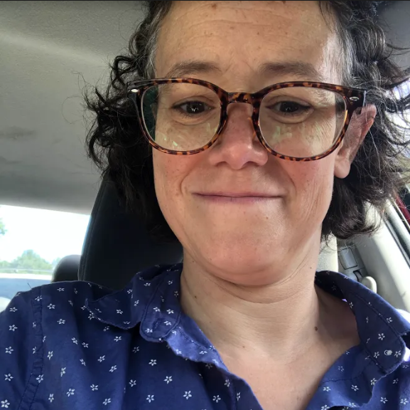 A woman wearing a dark blue button up shirt with white polka dots on it