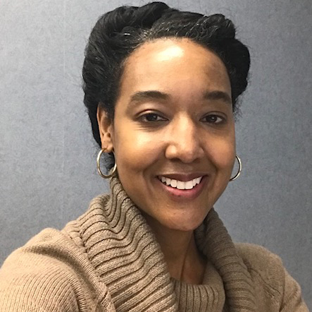 A woman wearing a brown sweater with gold earrings