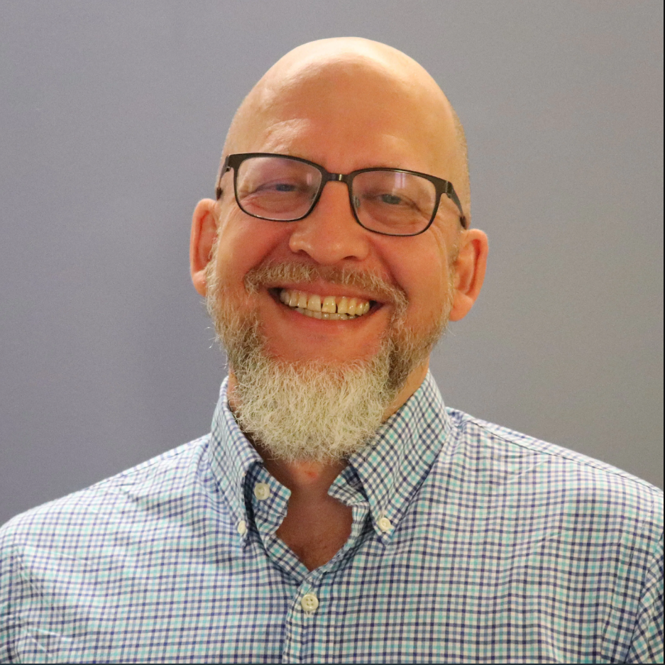 A man with a white goatee and a blue and white flannel shirt