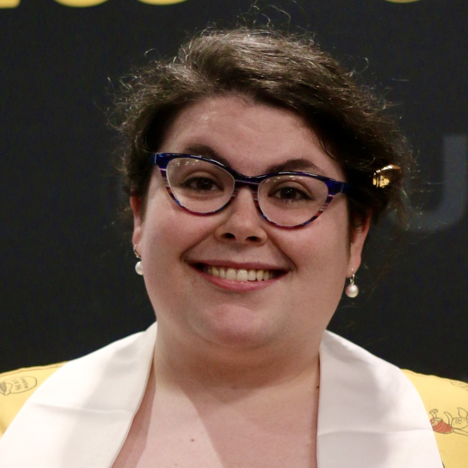 Rachel Brown wearing a gold jacket with glasses